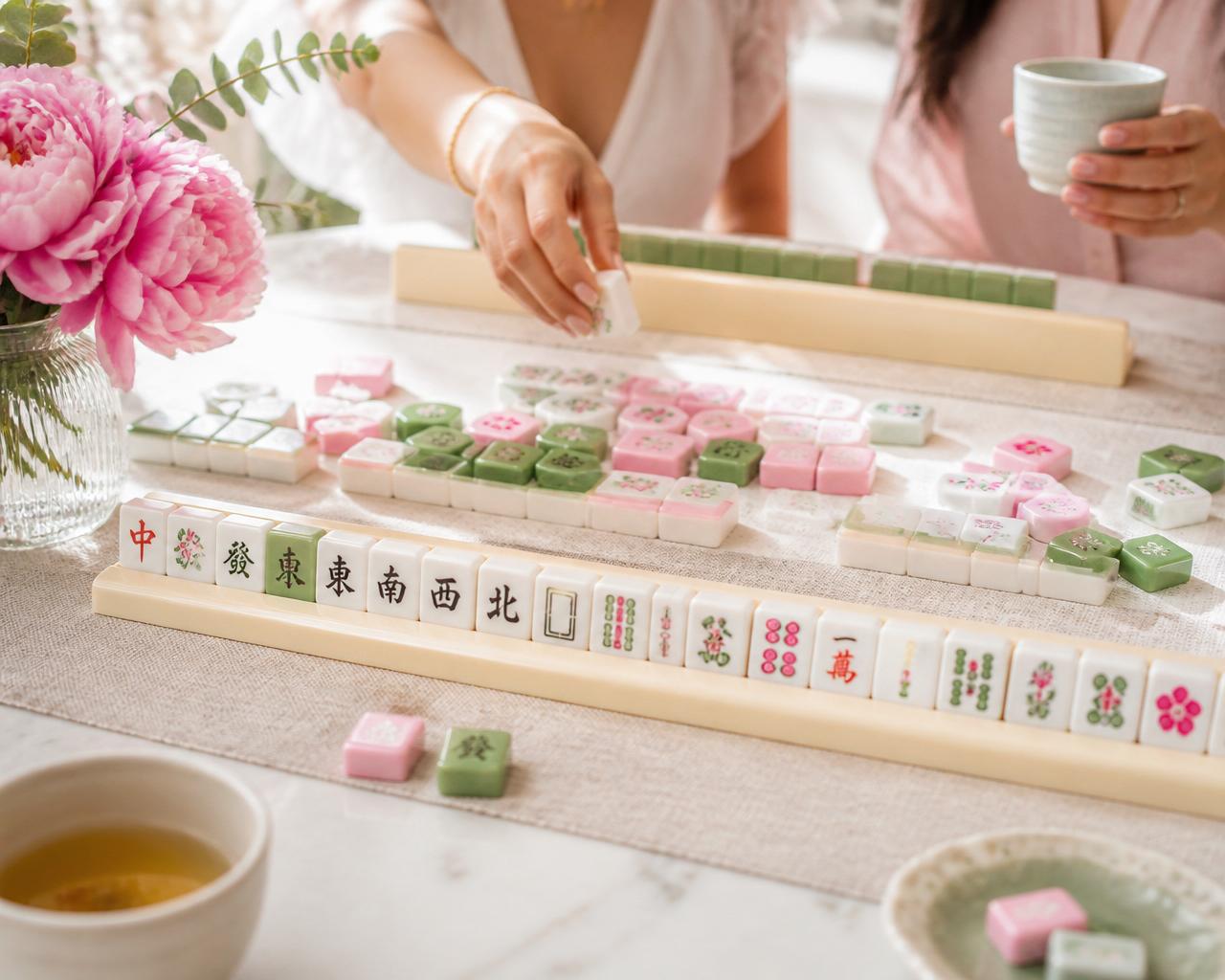 Pink, white, and green Mahjong tiles arranged on a light marble surface